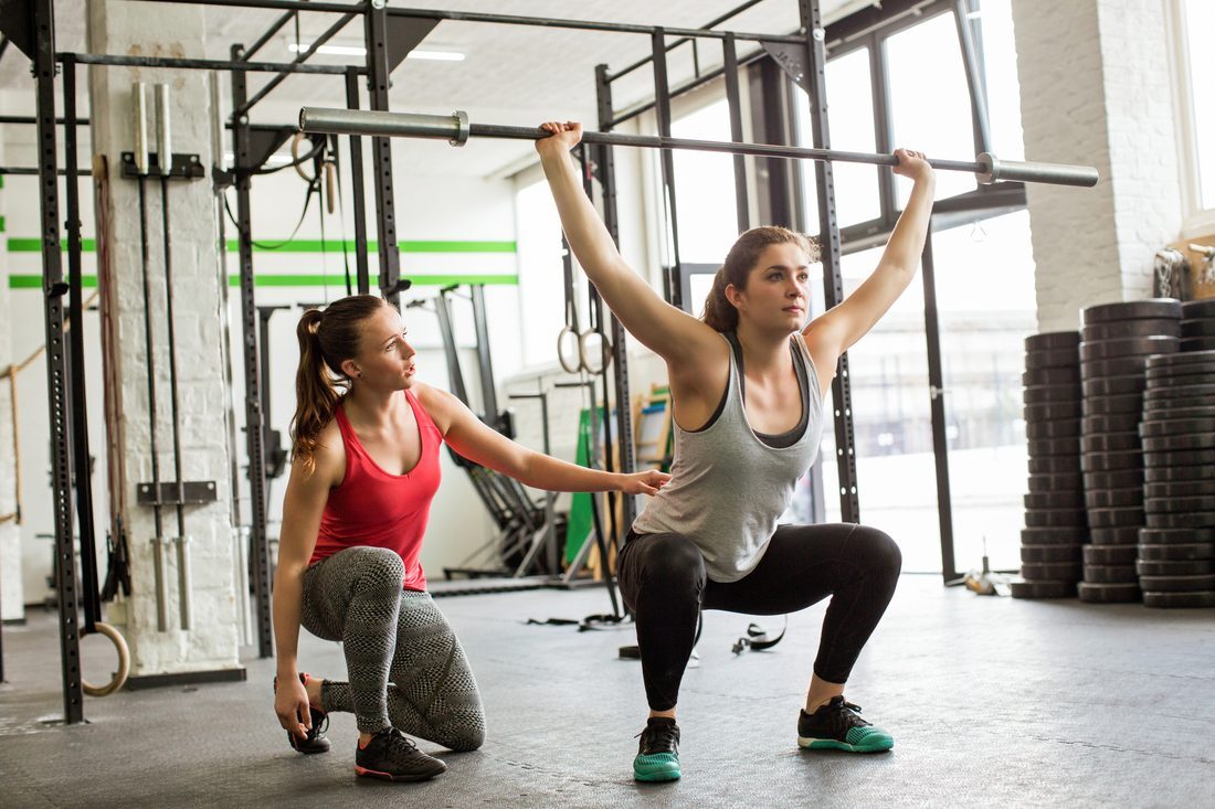 An NPTI instructor coaching a student through a barbell squat